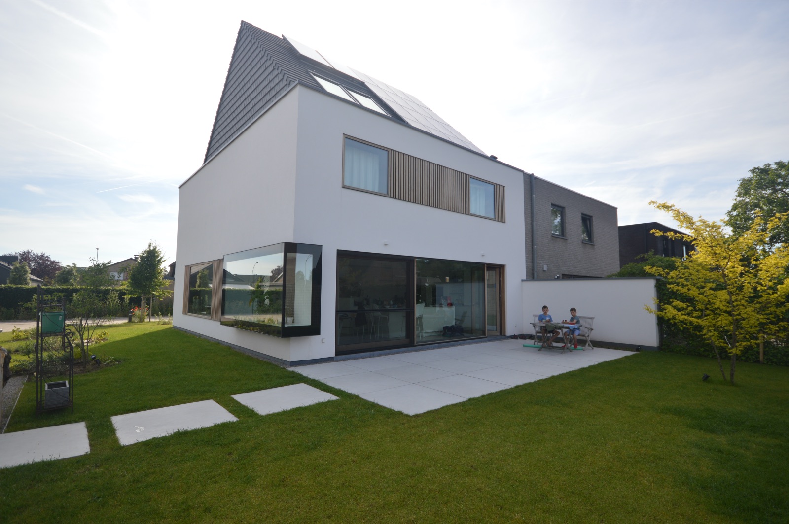 Moderne nieuwbouwwoning in wit met een zwart dak, realisatie van Plan Architectenbureau Brugge
