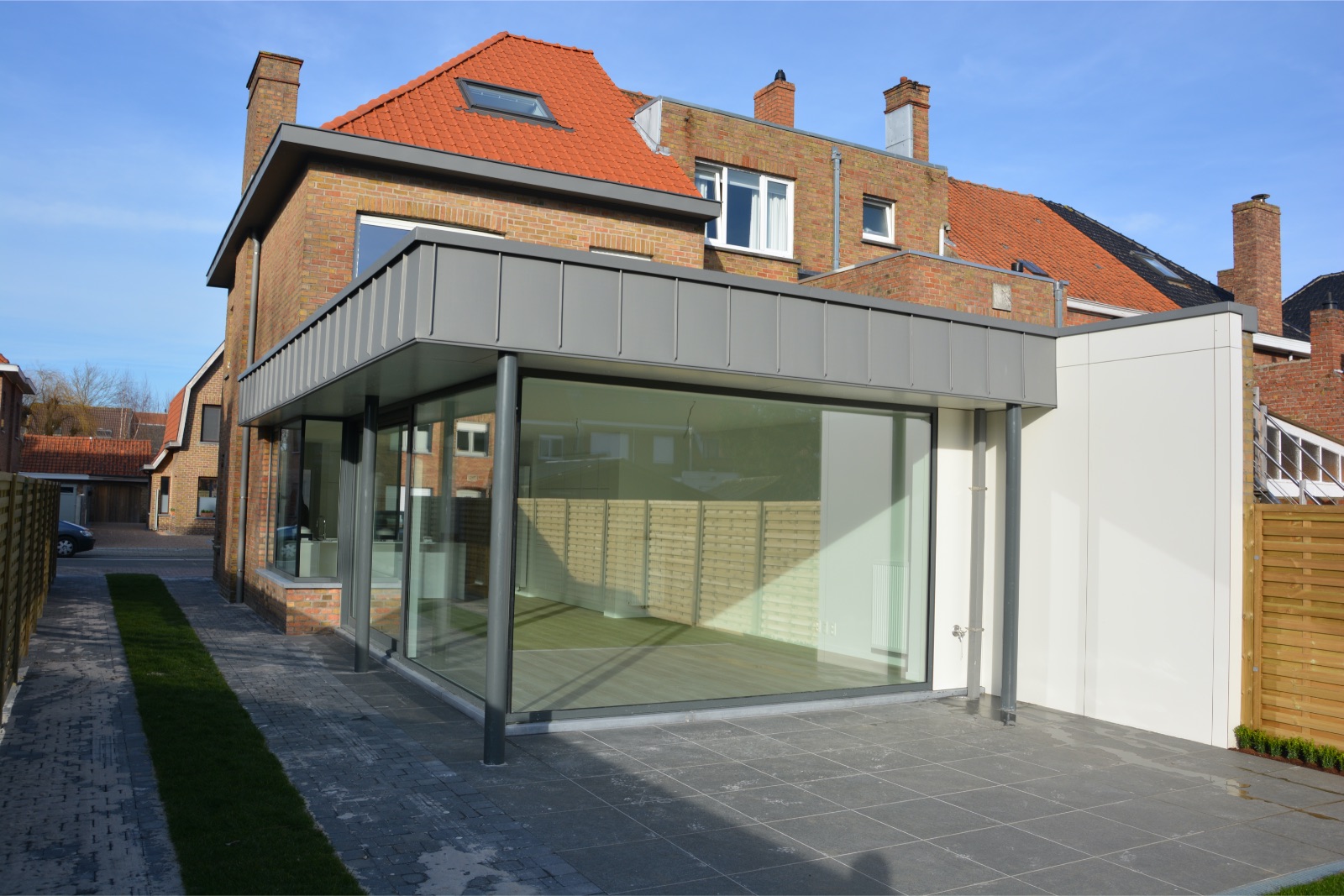 Renovatie van de achterbouw van een woning, woonuitbreiding met grote glaspartijen, realisatie van Plan Architectenbureau Brugge